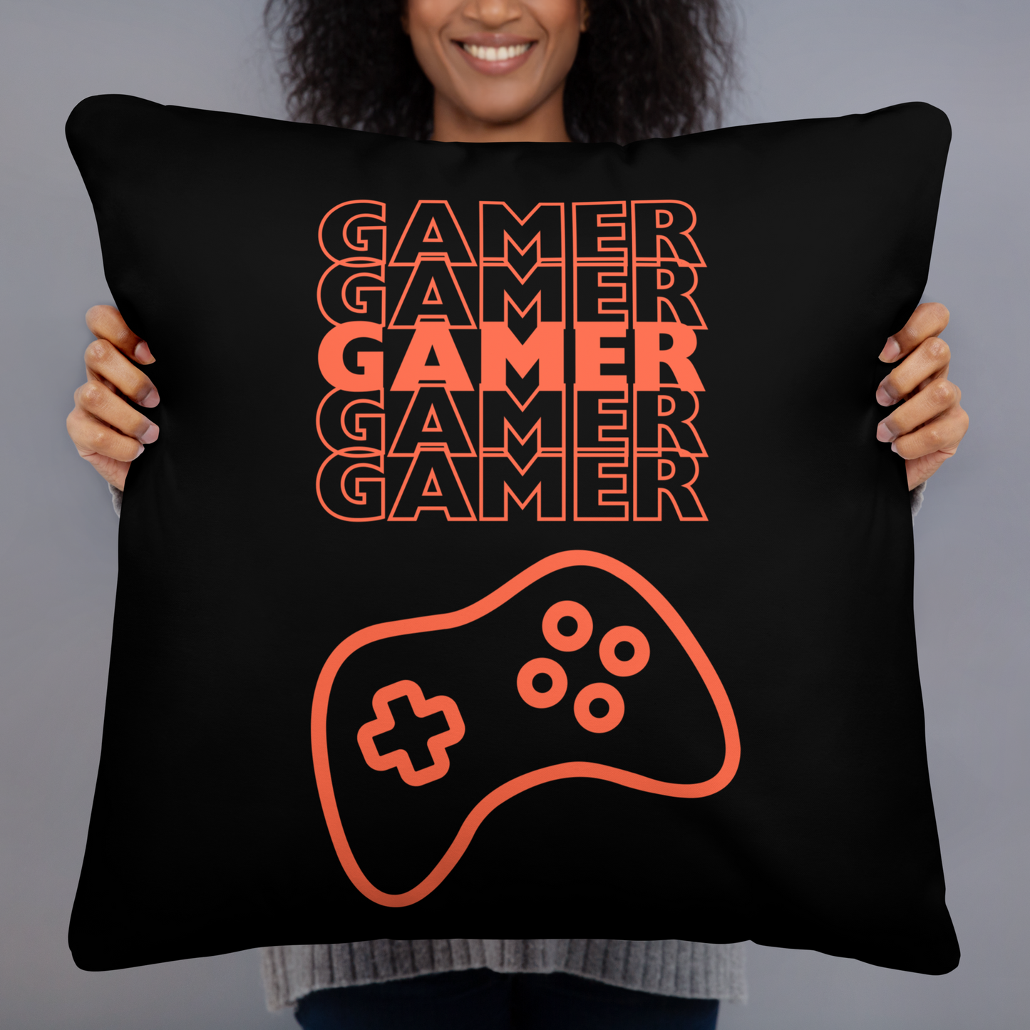 Black pillow with the word Gamer repeated 5 times in orange and an image of an orange-colored game controller